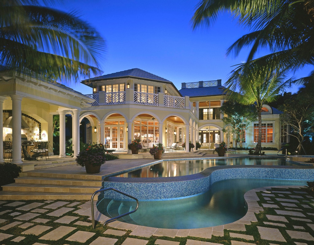 Luxury estate with arched colonnade and mosaic pool at dusk