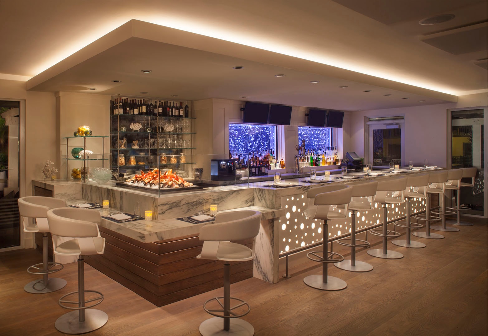 Upscale hotel restaurant bar with marble counter, illuminated dot panels, and seafood display