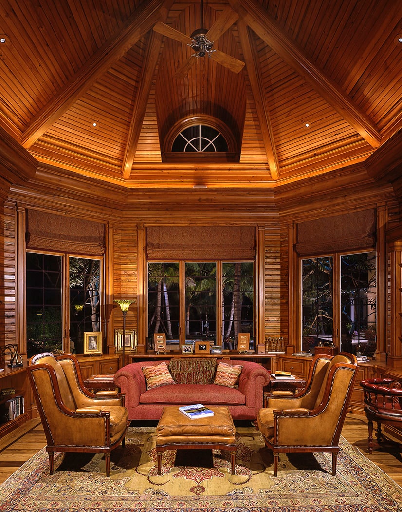 Octagonal wood-paneled study with vaulted cedar ceiling, leather wingbacks and red sofa