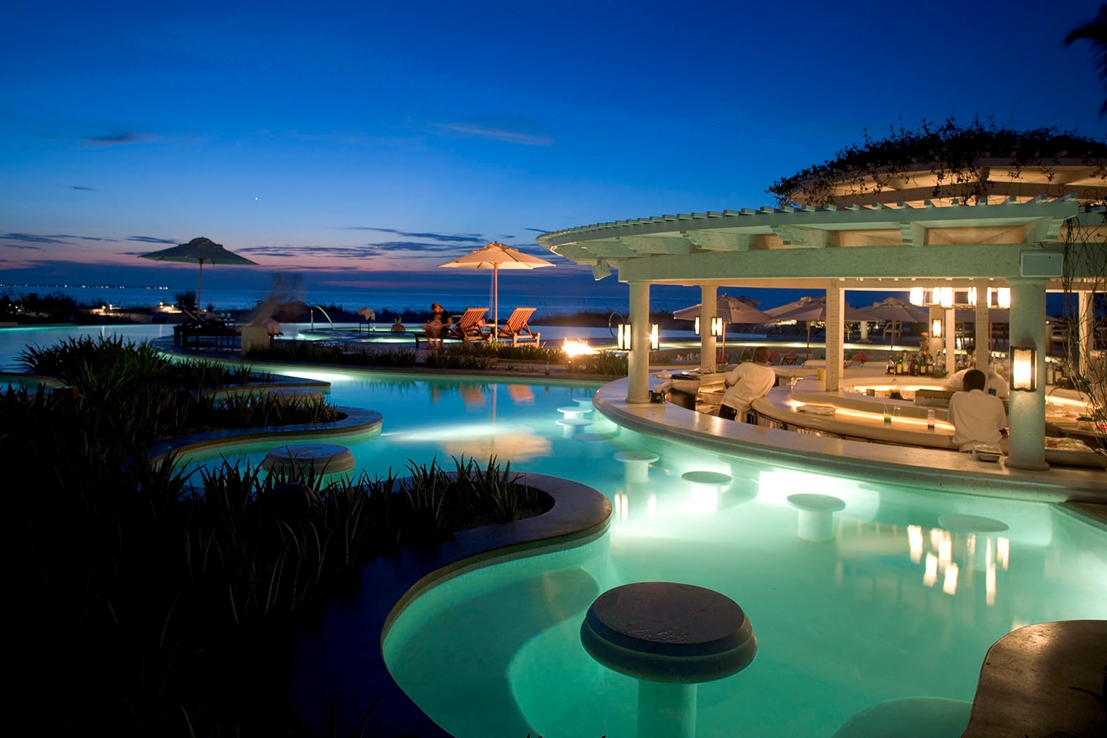 Resort infinity pool and terrace at dusk with ocean view