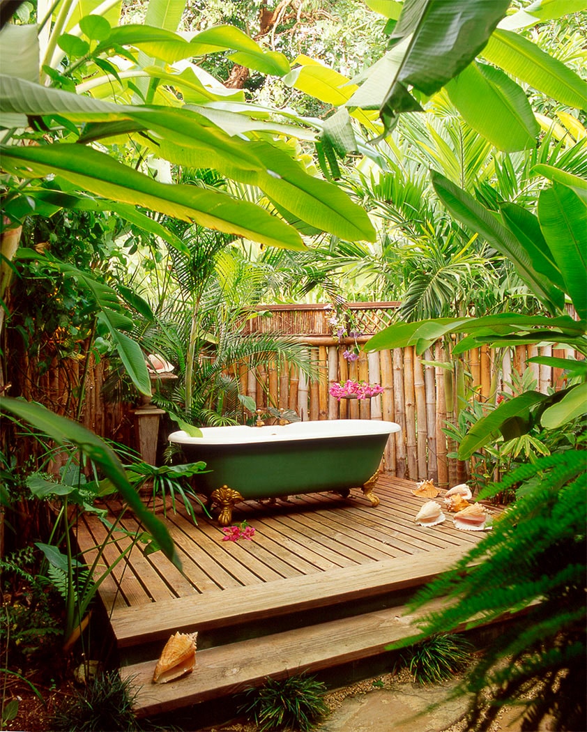 Outdoor tropical bath with clawfoot tub on wooden deck surrounded by jungle